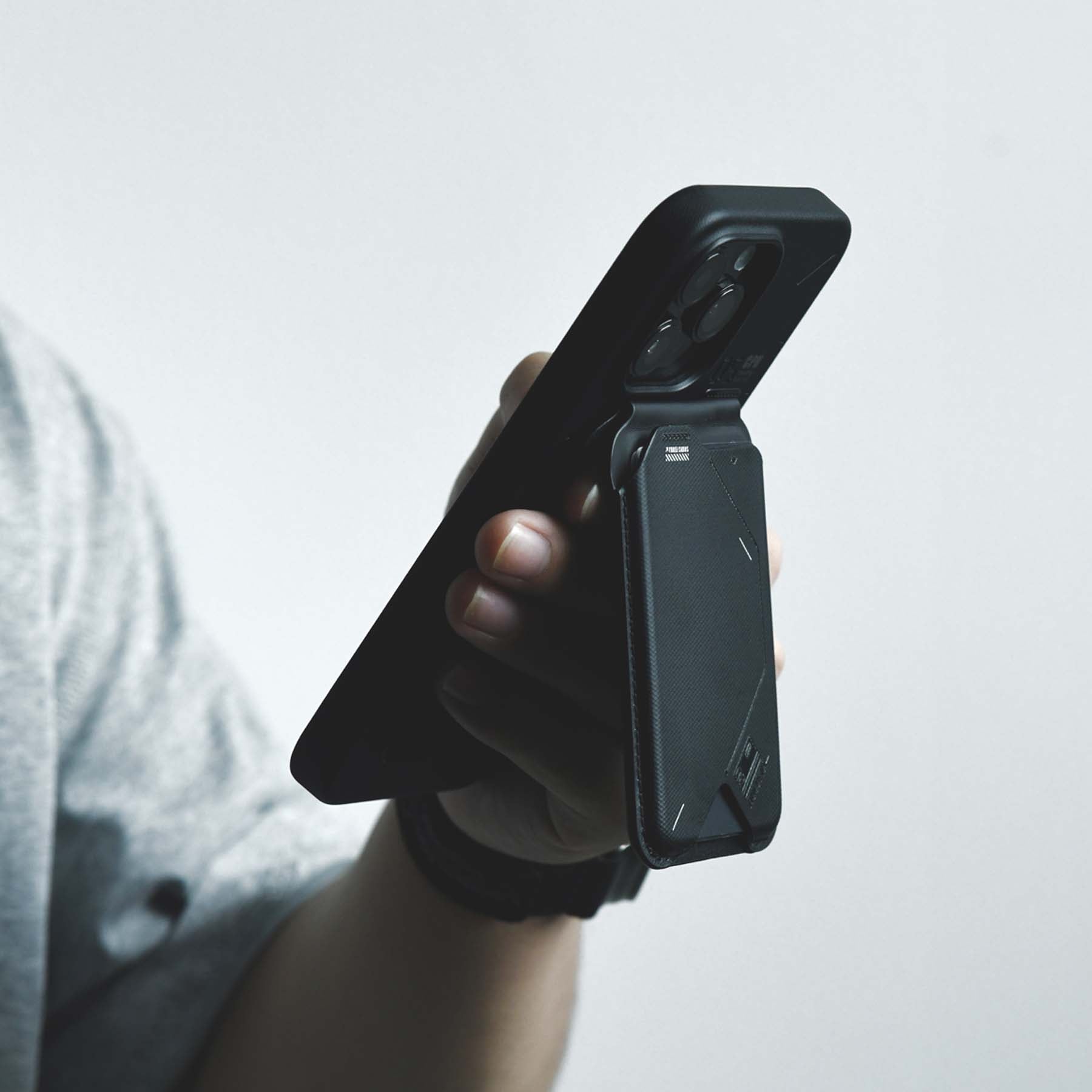 Close-up of a hand gripping an iPhone with the AULUMU G02 Magnetic Flip Wallet attached.