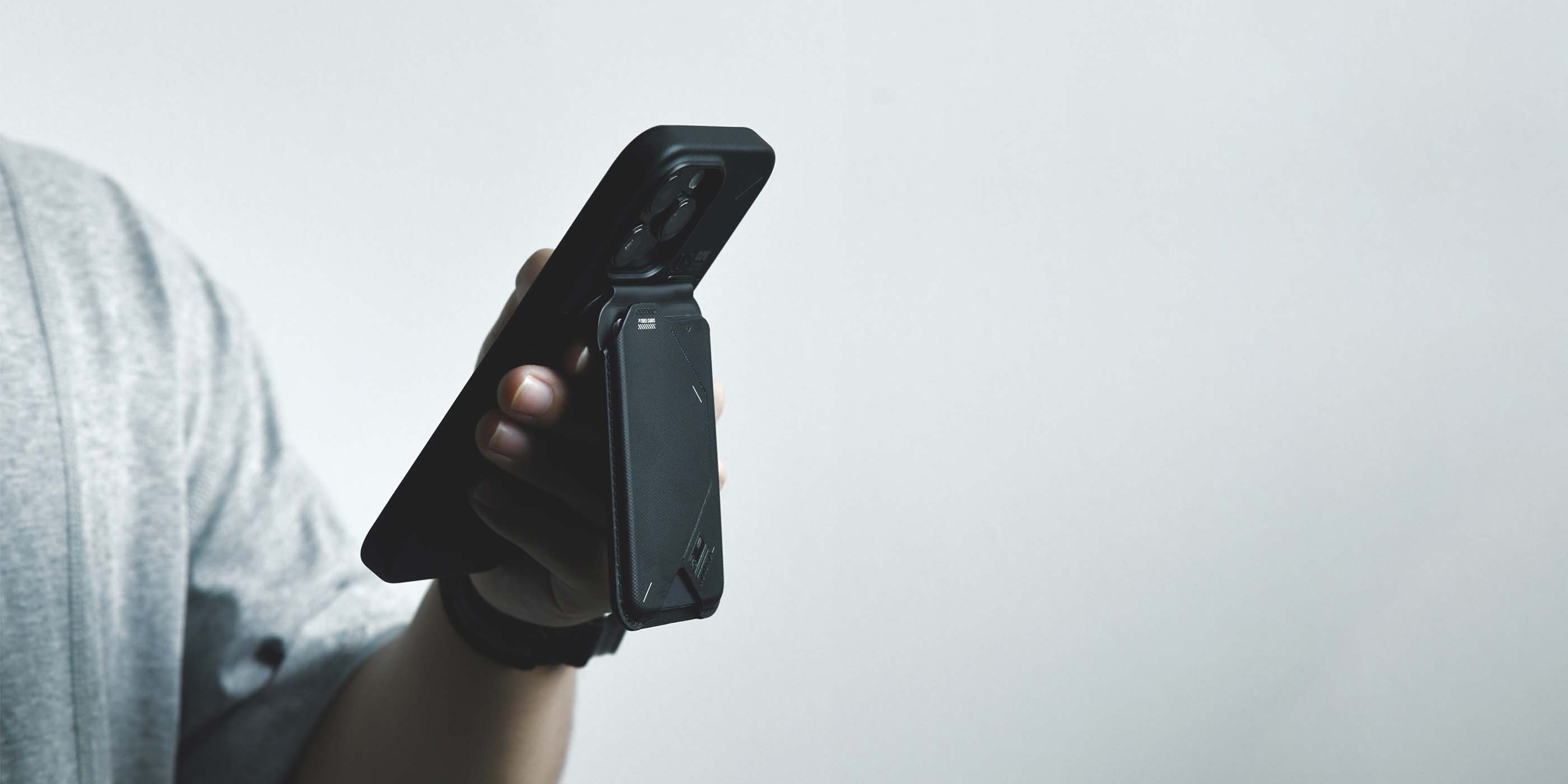 Person holding an iPhone using the AULUMU G02 Magnetic Flip Wallet as a magnetic grip.