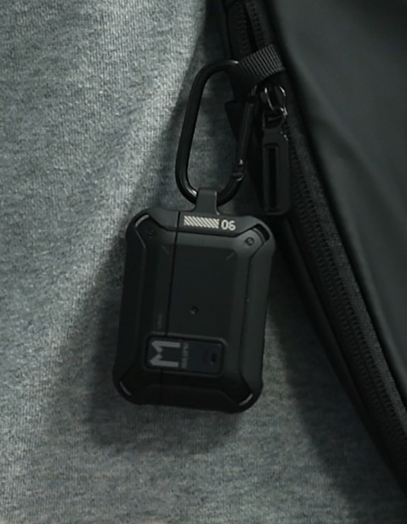 AULUMU A19 AirPods Pro case with lock and keychain clipped to a backpack strap